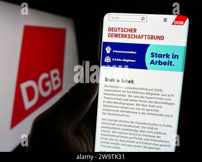 Personne tenant un smartphone avec la page Web de l'organisation allemande Deutscher Gewerkschaftsbund (DGB) avec logo. Concentrez-vous sur le centre de l'écran du téléphone. Banque D'Images