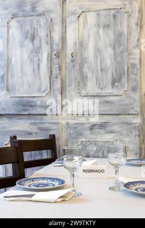 Panneau réservé au milieu de verres et assiettes sur une table dans un restaurant traditionnel. Banque D'Images