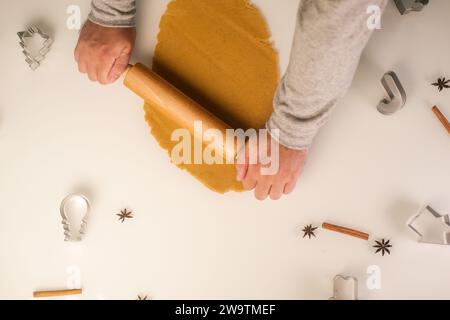 Vue de dessus des mains d'un homme roulant de la pâte de pain d'épice pour Noël. Banque D'Images