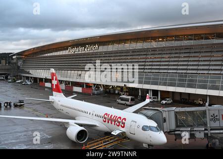 Avion de la compagnie suisse est garé à l'aéroport de Zurich. L'avion est connecté pour tirer le bras ou le connecteur pour embarquer le passager. Banque D'Images