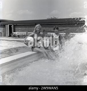 1964, juillet, historique, deux jeunes femmes dans leurs maillots de bain assis au bord de la piscine extérieure à la piscine en plein air Vale Park, Aylesbury, Bucks, Angleterre, Royaume-Uni. Banque D'Images