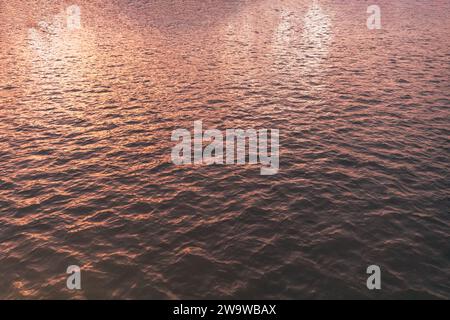 Texture de la surface de l'eau, lumière du coucher de soleil. Vue rapprochée de la mer du matin romantique beau fond. Vue rapprochée détaillée sur les surfaces de l'eau avec wav Banque D'Images