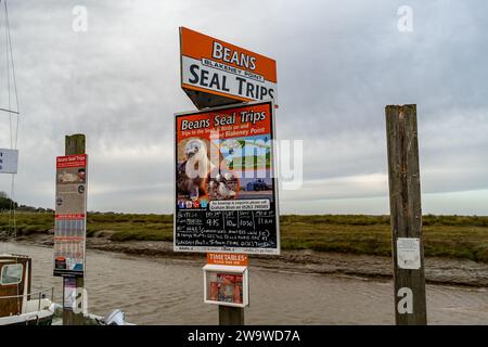 Blakeney, Norfolk, Royaume-Uni – décembre 29 2023. Seal regardant les publicités de voyage sur le quai et le front de mer Banque D'Images