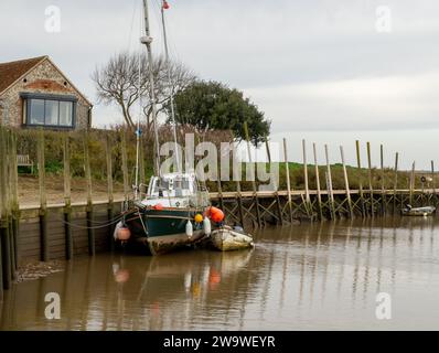 Blakeney, Norfolk, Royaume-Uni – décembre 29 2023. Un vieux voilier non identifiable amarré sur le quai à marée basse Banque D'Images