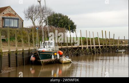 Blakeney, Norfolk, Royaume-Uni – décembre 29 2023. Un vieux voilier non identifiable amarré sur le quai à marée basse Banque D'Images