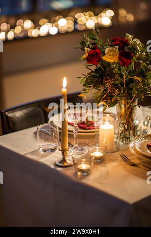 vacances, date romantique et concept de célébration - gros plan de table de fête servant pour deux avec des fleurs dans le vase et des bougies brûlant à la maison sur valent Banque D'Images