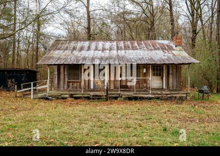 Vieille cabane rustique abandonnée en bois de pionnier avec un porche couvert, dans l'Alabama rural, États-Unis. Banque D'Images