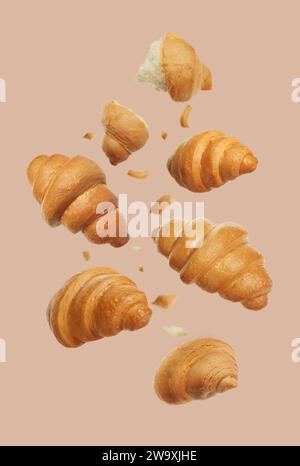 Délicieux croissants frais tombant sur fond beige Banque D'Images