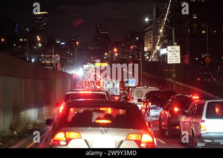 New York, États-Unis. 28 décembre 2023. Un trafic dense est vu sur l'autoroute de New York la nuit. La circulation routière à New York est célèbre, caractérisée par sa nature animée, rapide et souvent encombrée. Le réseau complexe de rues et avenues de la ville accueille un vaste réseau de véhicules, y compris des voitures, des taxis, des bus et des vélos, tous naviguant au milieu d'une mer de piétons. Les embouteillages quotidiens pendant les heures de pointe sont monnaie courante, en particulier autour des principales artères et des ponts, ce qui entraîne des temps de trajet prolongés et des frustrations occasionnelles pour les résidents et les v Banque D'Images