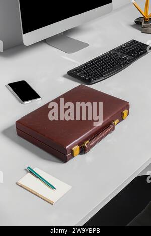 Workdesk montrant la différence entre la technologie passée et moderne, montrant un ordinateur et un téléphone portable, un bloc-notes et un stylo avec une mallette en cuir Banque D'Images