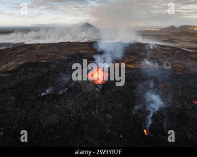 Lave coulant, magma chaud se déversant du cratère du volcan, vue latérale aérienne. Concepts d'éruption volcanique et terre islandaise de feu et de glace. Banque D'Images