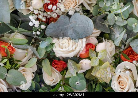 Superbe bouquet de mariée avec des roses orange et ivoire luxuriantes mélangées ensemble gracieusement enveloppées autour de feuilles verdoyantes et le souffle délicat de bébé Banque D'Images