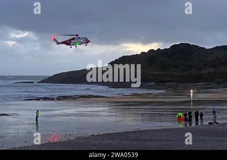 Swansea, Royaume-Uni. 31 décembre 2023. Hélicoptère de la Garde côtière atterrissant sur la plage de Langland Bay sur la péninsule de Gower près de Swansea cet après-midi pour assister à une victime pendant les conditions orageuses alors que la dernière lumière de 2023 s'estompe dans la nuit. Crédit : Phil Rees/Alamy Live News Banque D'Images