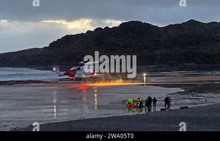 Swansea, Royaume-Uni. 31 décembre 2023. Hélicoptère de la Garde côtière atterrissant à Langland Bay sur la péninsule de Gower près de Swansea cet après-midi pour assister à une victime qui a été tirée de la mer consciente pendant les conditions orageuses alors que la dernière lumière de 2023 s'estompe dans la nuit. Crédit : Phil Rees/Alamy Live News Banque D'Images