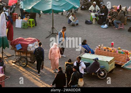 Vendeurs, musiciens, locaux et touristes se rassemblent sur la place Jemaa el fna, Marrakech, Maroc Banque D'Images