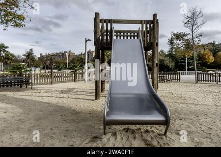 Un large toboggan métallique avec une structure en rondins de bois à l'intérieur d'une aire de jeux pour enfants Banque D'Images