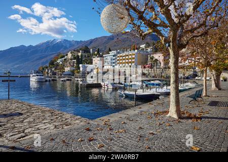 Vue sur le lac majeur en direction de Ronco sopra Ascona avec des bateaux à moteur et un platane (Platanus) de Lungolago, au bord du lac à Ascona, district Banque D'Images
