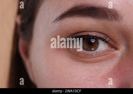 Vue rapprochée de femme avec de beaux yeux noisetier sur fond beige Banque D'Images