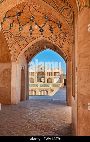 Vue de la porte d'entrée principale de la mosquée Agha Bozorg du 18e siècle à travers les arches du bâtiment principal. Kashan, Iran. Banque D'Images