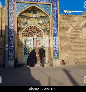 Un homme et une femme locaux entrent dans le sanctuaire du Sultan Amir Ahmad, l'un des lieux saints les plus importants de Kashan, en Iran. Banque D'Images