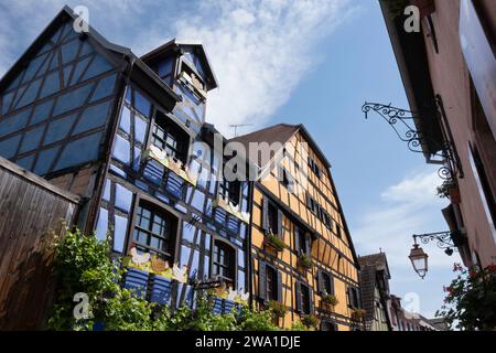 Idylliques maisons traditionnelles à colombages bleu et jaune dans le village touristique de Riquewihr en Alsace, France. Ciel bleu Banque D'Images