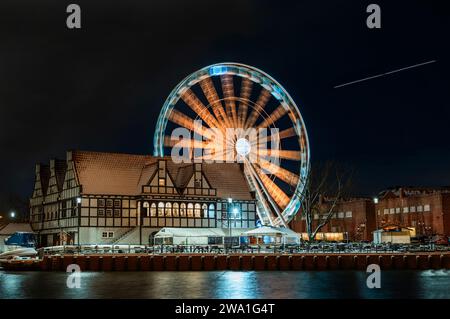 2023-02-04, avion volant à travers le ciel du soir. Remblai de soirée d'hiver Ferris roue Gdansk Pologne Banque D'Images