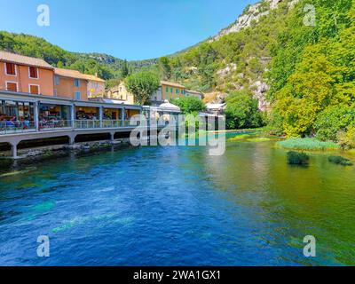 Centre du village de Fontaine de Vaucluse entouré par une nature colorée en été. Eaux claires et cristallines de la source du ruisseau Sorga. Banque D'Images