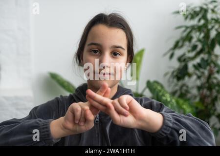 Belle fille sourde souriante utilisant le langage des signes. Banque D'Images