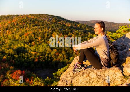 Jeune femme profitant de la vue du sentier sur Beehive à l'automne dans le parc national Acadia, Maine, USA Banque D'Images