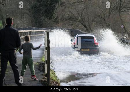 Lacock, Wiltshire, Royaume-Uni. 1 janvier 2024. La rivière Avon à Lacock a fait éclater ses berges sur inondé la route hors du village. Le conseil est de ne pas conduire à travers les eaux de crue mais la route est praticable avec prudence. Crédit : JMF News/Alamy Live News Banque D'Images