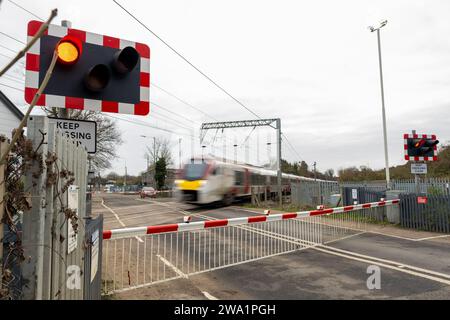 Un train à grande vitesse du Greater Anglia passe devant un passage à niveau fermé à Great Blakenham Claydon, Ipswich, Suffolk en décembre 2023 Banque D'Images
