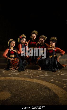 un groupe de danseurs attirent l'attention dans des costumes rouges frappants et s'assoient ensemble la nuit Banque D'Images