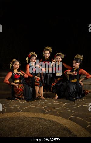 un groupe de danseurs attirent l'attention dans des costumes rouges frappants et s'assoient ensemble la nuit Banque D'Images