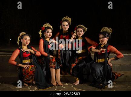 un groupe de danseurs attirent l'attention dans des costumes rouges frappants et s'assoient ensemble la nuit Banque D'Images