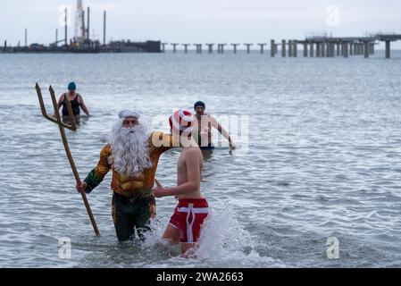 Prerow, Allemagne. 01 janvier 2024. Habillé en Neptune, Tim Bergelt sort de la mer Baltique à 5 degrés avec d'autres nageurs amateurs. Le jour de l'an, des centaines de vacanciers ont de nouveau participé à la traditionnelle manifestation balnéaire de la péninsule de Fischland-Darß-Zingst. Crédit : Stephan Schulz/dpa/Alamy Live News Banque D'Images