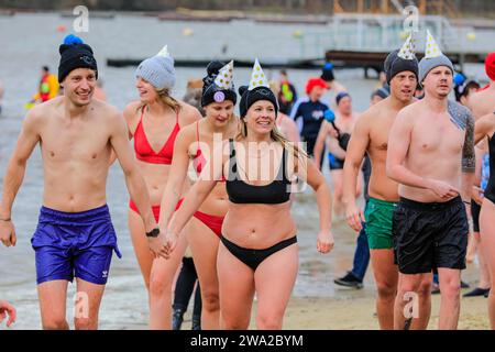 Haltern, Allemagne. 01 janvier 2024. Les participants bravent l'eau froide. Un record de 590 nageurs inscrits, le plus grand nombre depuis de nombreuses années, plus les visiteurs, s'amusent à la natation annuelle du jour de l'an, un événement de natation en eau libre qui a lieu au lac Haltern dans la ville de Haltern, Rhénanie du Nord Westphalie. Malgré le temps imprévisible avec la pluie, beaucoup bravent la course le long de la plage et dans le lac froid en costumes pour célébrer la nouvelle année avec style. Tous les profits de l'événement vont à des organismes de bienfaisance locaux. Crédit : Imageplotter/Alamy Live News Banque D'Images