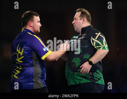 Luke Littler célèbre la victoire sur Brendan Dolan (à droite) le 14e jour du Championnat du monde de fléchettes Paddy Power à Alexandra Palace, Londres. Date de la photo : lundi 1 janvier 2024. Banque D'Images