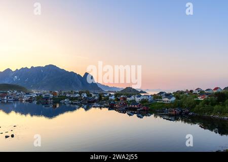 Nuit d'été tranquille à Reine, îles Lofoten, Norvège, avec des maisons colorées reflétées dans des eaux calmes sous un ciel crépusculaire doux Banque D'Images