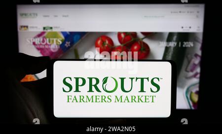 Personne détenant un téléphone intelligent avec le logo de la société de vente au détail américaine Sprouts Farmers Market Inc. Devant le site Web. Concentrez-vous sur l'affichage du téléphone. Banque D'Images