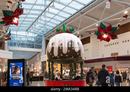 Les acheteurs achètent pour Noël en décembre à Porchester Square, place du Festival, avec une énorme décoration de pudding de Noël. Basingstoke, Royaume-Uni Banque D'Images
