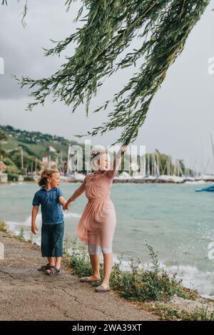 Doux petits enfants jouant au bord du lac sur une journée très venteuse sous la pluie d'été. Image prise sur le lac Léman, Lausanne, Suisse Banque D'Images