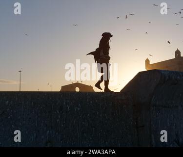 Homme en costume de pirate marche les murs de la ville près du fort un soir d'hiver dans la ville d'Essaouira, Maroc, le 1er janvier 2024 Banque D'Images