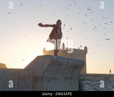 Homme en costume de pirate marche les murs de la ville près du fort un soir d'hiver dans la ville d'Essaouira, Maroc, le 1er janvier 2024 Banque D'Images