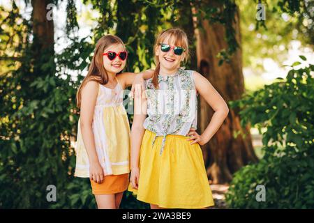 Portrait en plein air de deux drôles préadolescentes portant des lunettes de soleil Banque D'Images