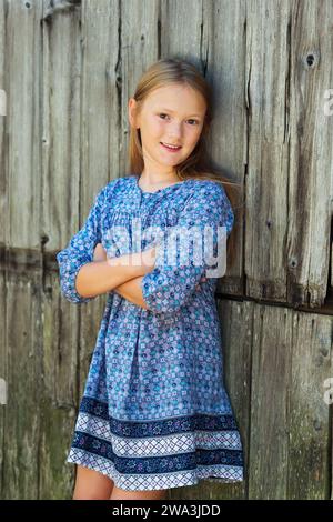 Portrait de mode en plein air d'une jolie petite fille portant une robe bleue Banque D'Images