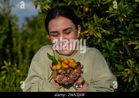 La jeune fille tenant les kumquats dans sa paume. Banque D'Images