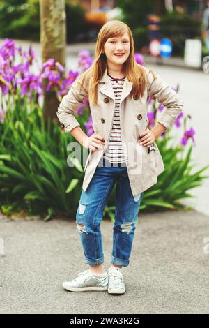 Portrait de mode en plein air de fille hipster de 9-10 ans portant un trench élégant Banque D'Images