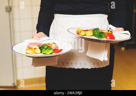 Waiter carrying deux plaques avec plat de viande sur certains événement festif, parti, réception de mariage ou événement Banque D'Images