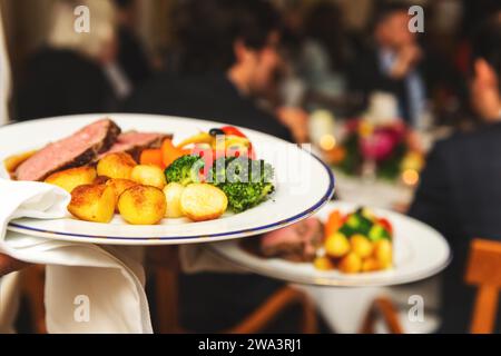 Waiter carrying deux plaques avec plat de viande sur certains événement festif, parti, réception de mariage ou événement Banque D'Images