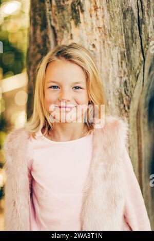 Portrait en plein air d'adorable petite fille de 7 ans, cheveux blonds, yeux bleus, portant des vêtements roses Banque D'Images